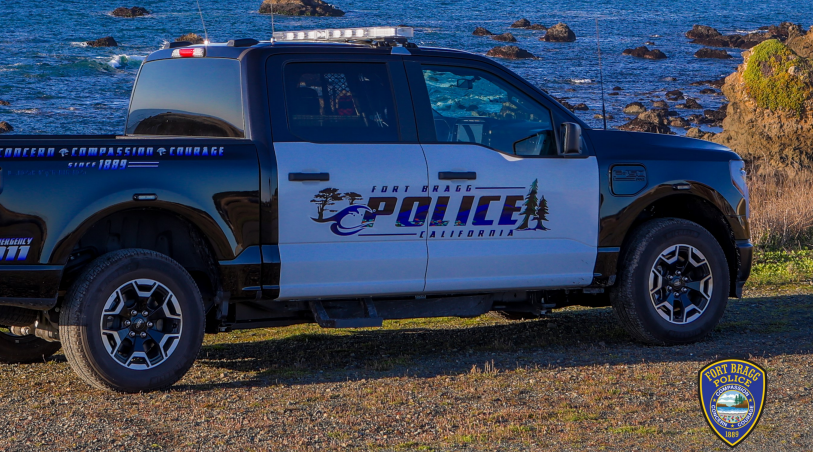 A police vehicle stationed on a dirt road adjacent to the ocean